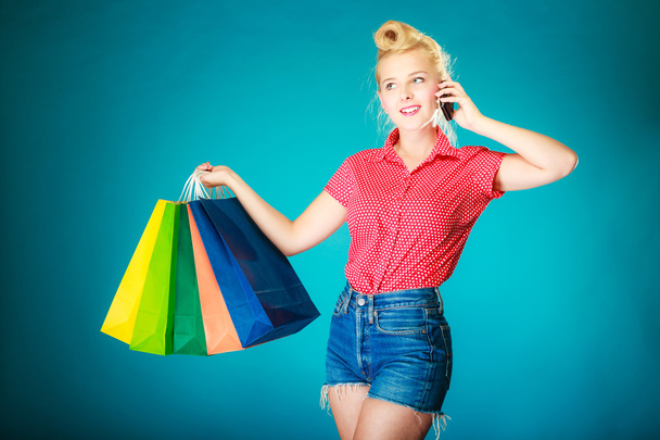 Pinup girl with shopping bags calling on phone - Fotó, kép