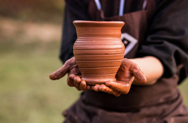 Руки гончара держат глиняный горшок на мастерской - Фото, изображение