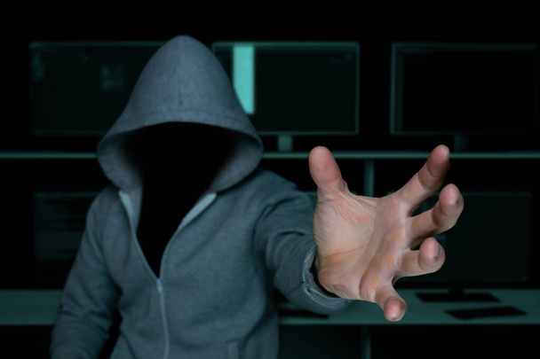 unknown hacker in the hood, pulls his hand to commit theft - Photo, Image