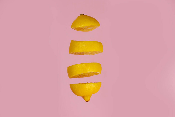 Levitating lemon sliced on pink background. Four pieces separated in air - Photo, Image