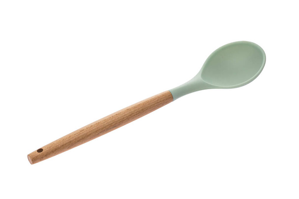 Kitchen tool in the form of a spoon made of green plastic with a wooden handle for cooking - Foto, immagini