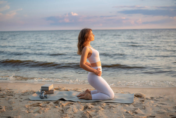 adorable jeune femme sportive pratique le yoga sur la plage. yoga en dehors de la maison. l'un des assanas de yoga.  - Photo, image