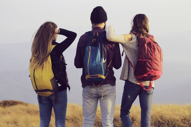 Friends of man with two pretty sexy cute girls or women standing with colorful backpacks a on mountain top. - 写真・画像