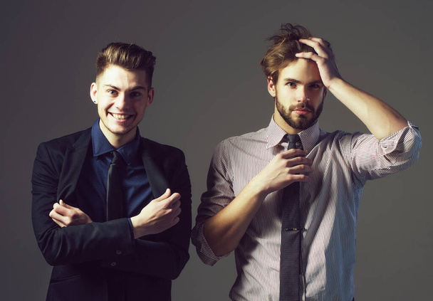 Handsome young businessmen friends in jacket, shirt and tie has fashionable hair and serious and smiling face on grey background. Stylish sexy men or guys in studio - Φωτογραφία, εικόνα