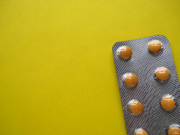 Heap of pills on yellow background. Tablets, vitamins and blisters with capsules for the treatment of diseases. Copy space - 写真・画像