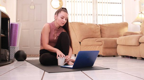 Hausleben während der Pandemie - Frau arbeitet am Laptop im Wohnzimmer.  - Foto, Bild