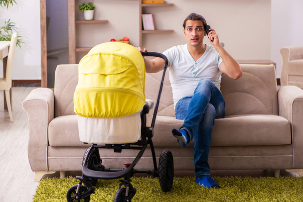 Jovem empreiteiro masculino cuidando de recém-nascido em casa - Foto, Imagem