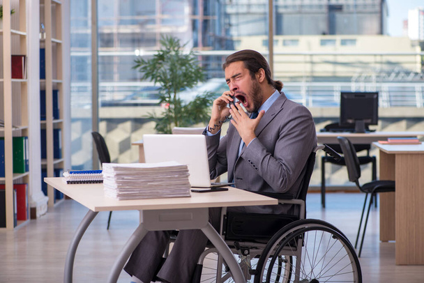 Joven empleado masculino en silla de ruedas que trabaja en la oficina - Foto, Imagen