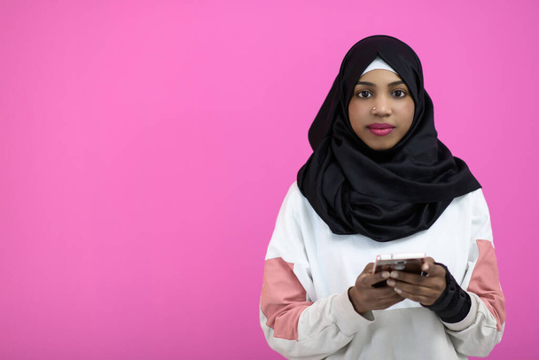 afro woman uses a cell phone in front of a pink background - Foto, Imagen