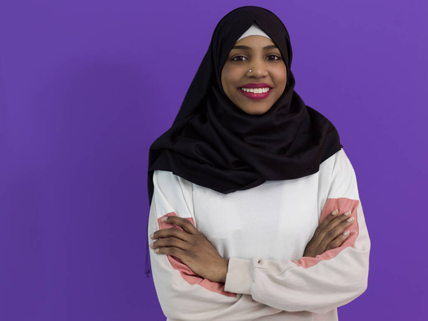 portrait of african muslim woman wearing hijab and traditional muslim clothes posing in front of purple background - Foto, imagen