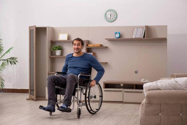Młody mężczyzna na wózku inwalidzkim cierpiący w domu - Zdjęcie, obraz