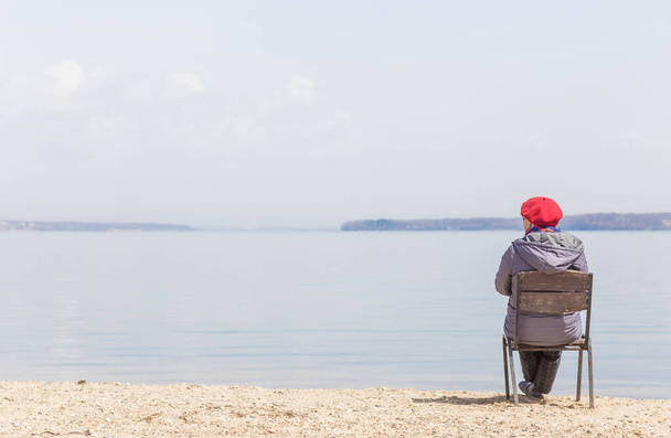 Elderly woman admires sea view on a beach in sunny day. Travel concept. Loneliness concept. - Valokuva, kuva