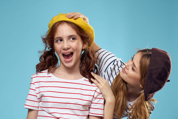 Mom and daughter striped T-shirts hugs fun lifestyle blue background - Fotó, kép