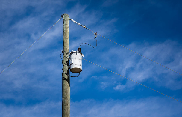 Kuzey Amerika 'da kırsal bir arazide trafoya ve elektrik hatlarına sahip tahta bir elektrik direği.. - Fotoğraf, Görsel