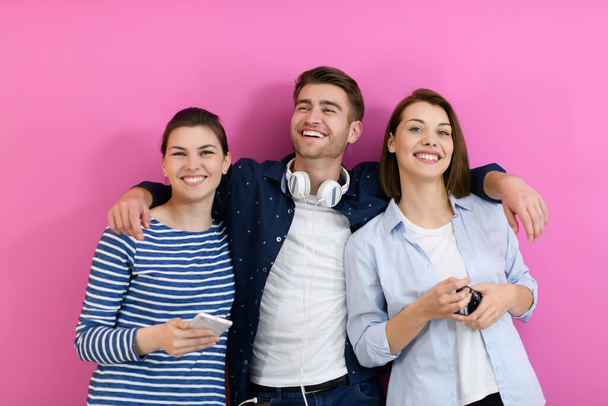 a group of friends have fun and dance while using a cell phone and headphones isolated on a pink background - Fotografie, Obrázek