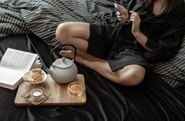 Женщина завтракает с чаем и печеньем, лежит в постели в выходной. - Фото, изображение