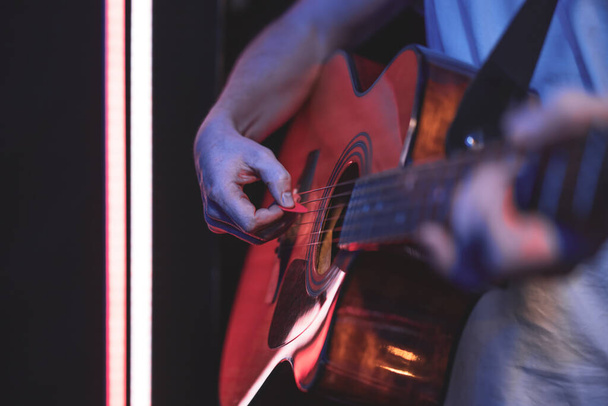 Un homme joue de la guitare acoustique dans une pièce sombre. Spectacle live, concert acoustique. - Photo, image