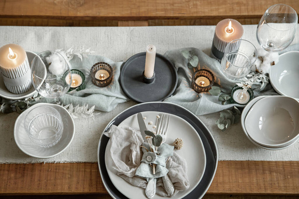 Az ünnepi asztaldíszítés részletei evőeszközökkel, tányérral és gyertyákkal gyertyatartókban. - Fotó, kép