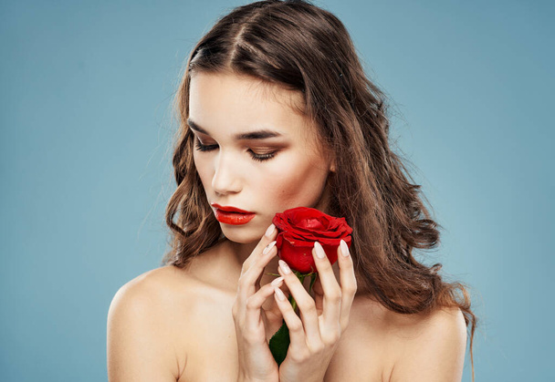 Frau Modell mit roter Rose nahe Gesicht auf blauem Hintergrund - Foto, Bild