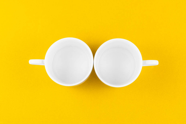 Empty white coffee cup isolated on yellow background. - Foto, imagen