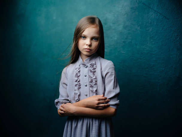 Pretty girl in a gray sundress with loose hair on a turquoise background - Fotoğraf, Görsel