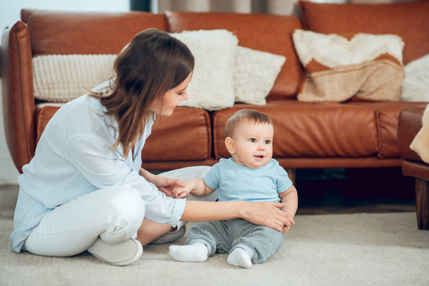 Attentive mother supporting child sitting on floor - Photo, Image