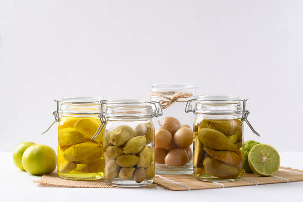 Házi készítésű különböző pácolt gyümölcs egy üveg üveg fehér alapon, Trópusi tartósított élelmiszer, Emésztésre szánt élelmiszer - Fotó, kép
