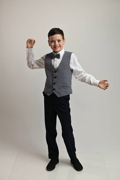 Portrait of a boy in a suit with a bow tie on a white background in full growth - 写真・画像