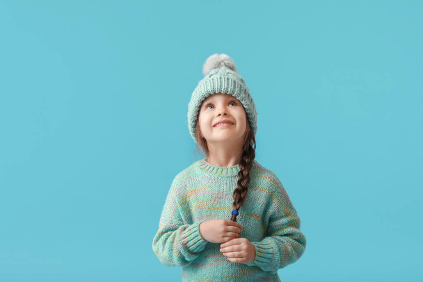 Stylish little girl in winter clothes on color background - Foto, Imagen