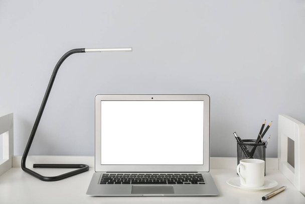 Mesa com laptop e lâmpada perto da parede de luz no quarto - Foto, Imagem
