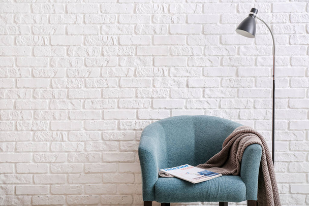 Armchair and lamp near light brick wall in room - Photo, Image