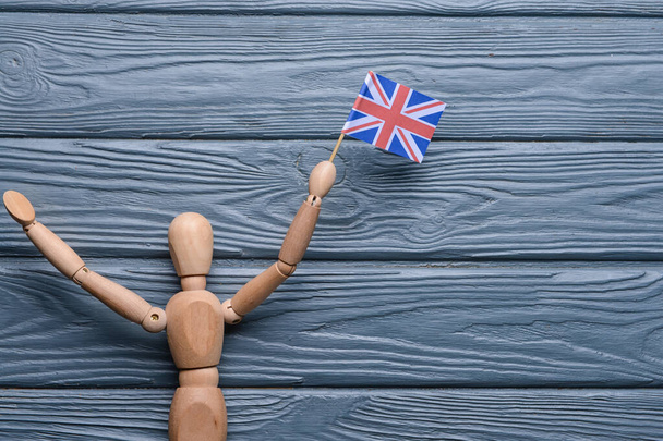 Menselijk beeldje met nationale vlag van het Verenigd Koninkrijk op houten ondergrond - Foto, afbeelding