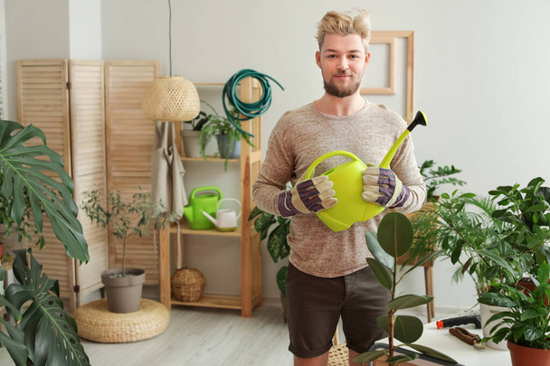 Junger Mann pflegt Pflanzen zu Hause - Foto, Bild