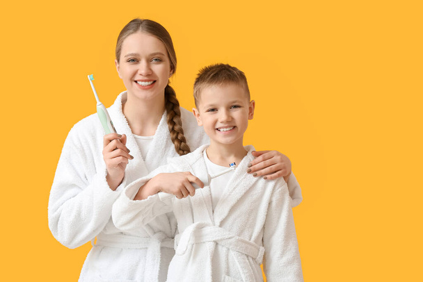 Mutter und kleiner Sohn beim Zähneputzen auf farbigem Hintergrund - Foto, Bild