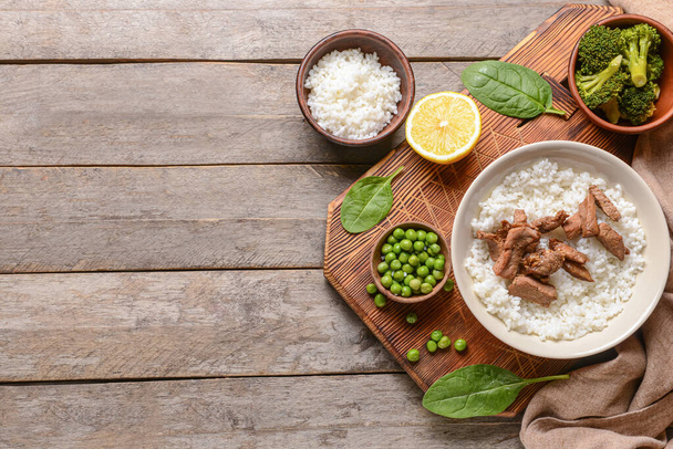 Teller mit leckerem Reis und Fleisch auf Holzgrund - Foto, Bild