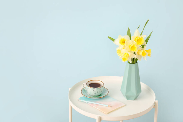 Vase with beautiful daffodils on table against color background - Photo, Image