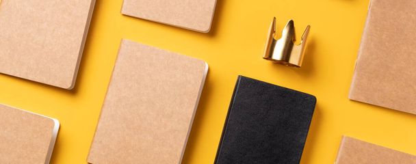 content is king for online marketing concept.top view of notebook with golden crown align with kraft paper book in pattern on yellow table background - Foto, imagen