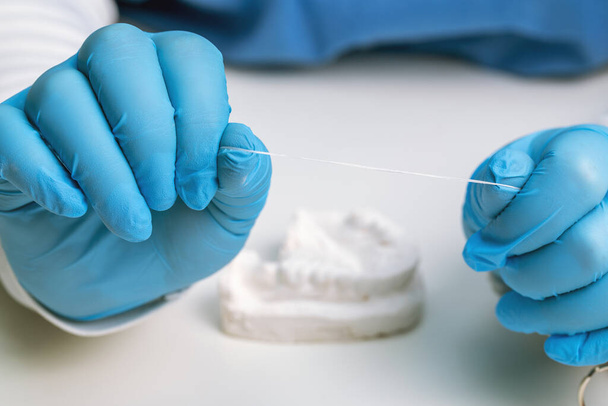 dentist holding dental floss against white desktop background, oral hygiene products - Фото, изображение