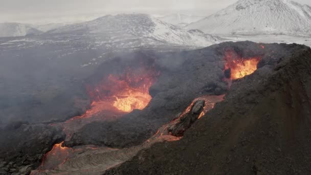 Flug in der Nähe des Vulkans mit schneebedeckten Bergen4k Drohne, aufgenommen aus Island mit heißer Lava und Magma aus dem Krater, April 2021  - Filmmaterial, Video