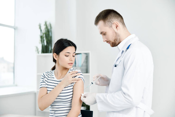 médico masculino em um casaco branco injeções no ombro de uma mulher paciente vacinação vívida - Foto, Imagem