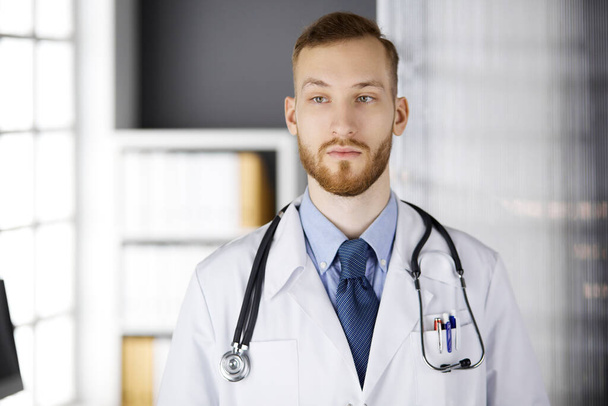 赤ひげの医者は彼の職場の近くの診療所にまっすぐ立っている。医師の肖像画。医学、医療 - 写真・画像