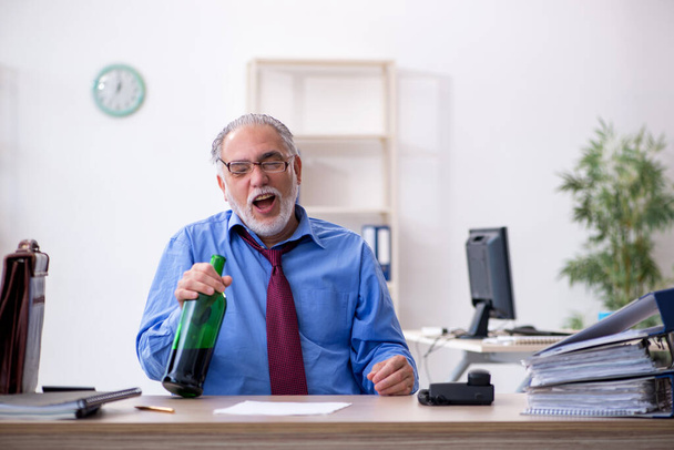 Alte männliche Angestellte trinkt Alkohol im Büro - Foto, Bild