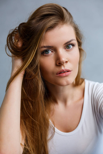 Close up portrait of a beautiful young woman. Emotional photo of a girl. Dressed in a white t-shirt - Foto, Imagen