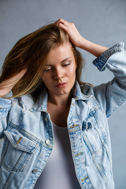 Close up portrait of a beautiful young woman. Emotional sad photo of a girl. Dressed in a white T-shirt and a jeans jacket - Fotoğraf, Görsel
