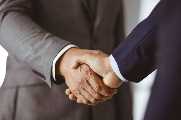 Business people in office suits standing and shaking hands, close-up. Business communication concept. Handshake and marketing - Foto, Bild