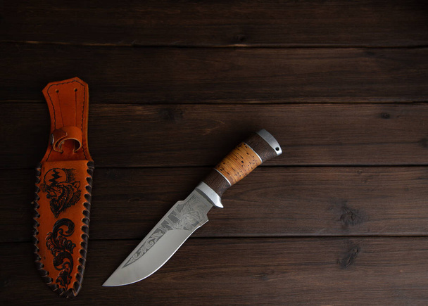 hunting knife on a wooden table - Fotó, kép