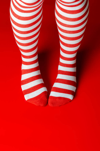 Χριστουγεννιάτικη ιδέα. Σάντα πόδια γυναίκα στο κόκκινο φόντο - Φωτογραφία, εικόνα