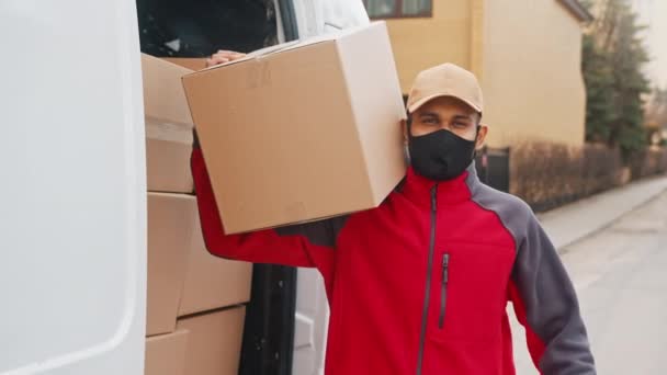 Курьер доставляет посылки во время ковид19, человек в маске при перевозке коробок - Кадры, видео