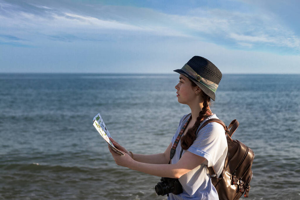 la chica con la cámara, la mochila y el sombrero mirando el mapa. - Foto, Imagen