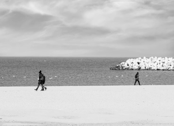 Черно-белая фотография с людьми, идущими в противоположном направлении - Фото, изображение